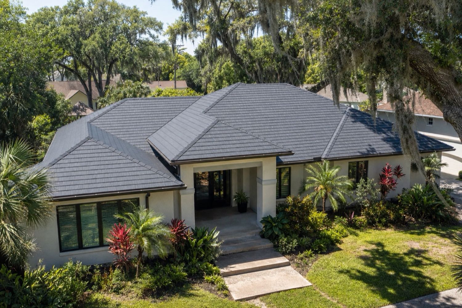 Single-story Jacksonville home with a charcoal slate-profile metal shingle roof under live oaks